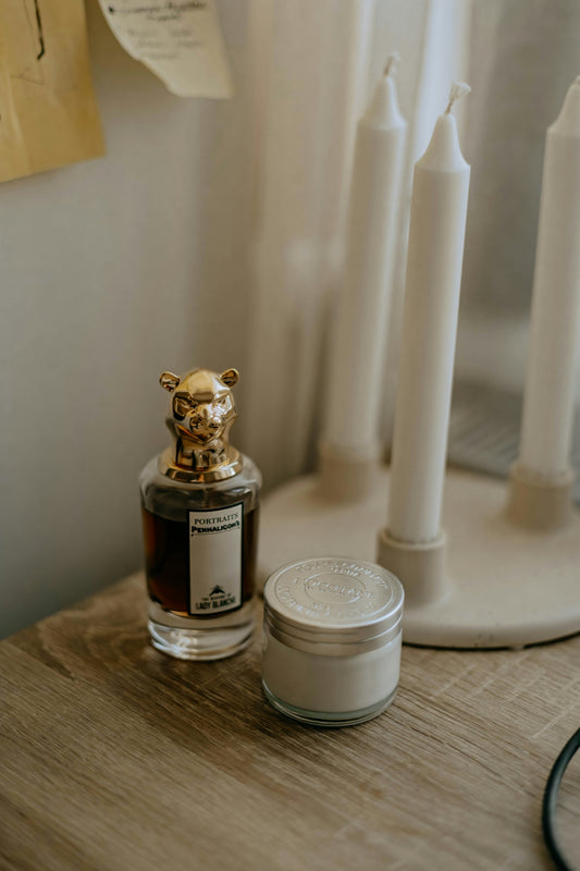 a table with a candle and a bottle of perfume on it